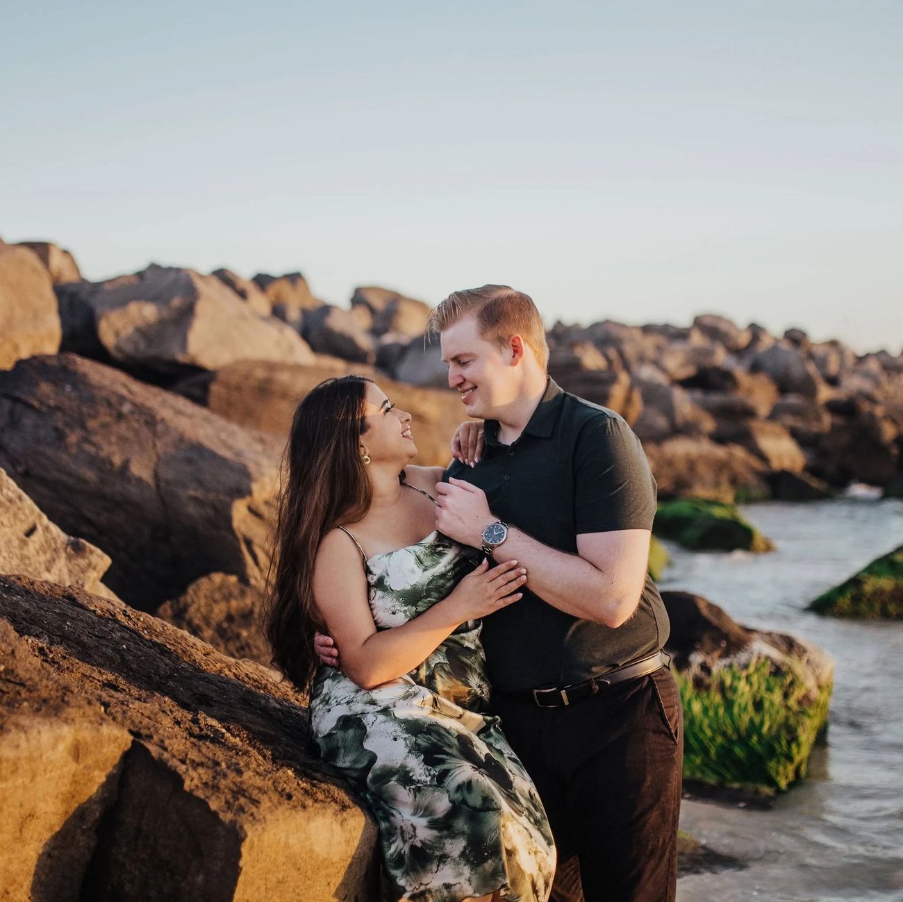 Allison and Daniel laughing together on the rocks at golden hour