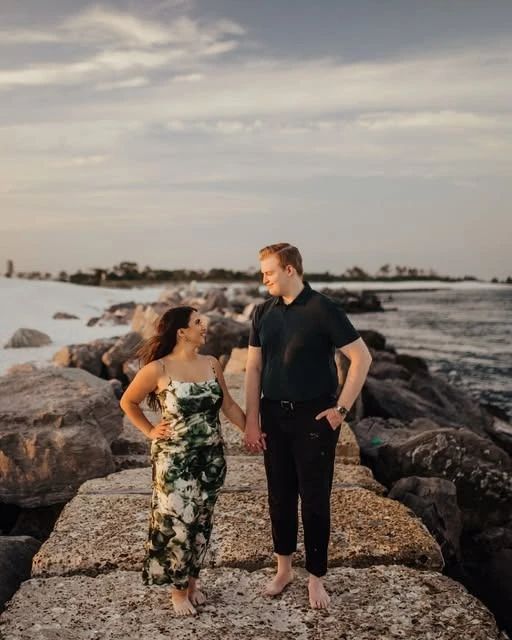Allison and Daniel standing barefoot on the jetty rocks