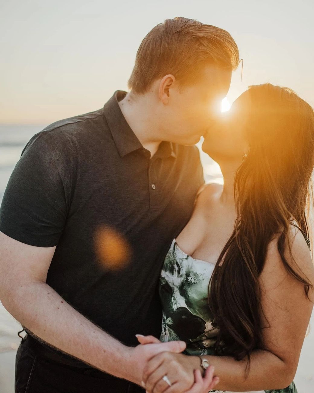 Allison and Daniel kissing as the sun sets behind them